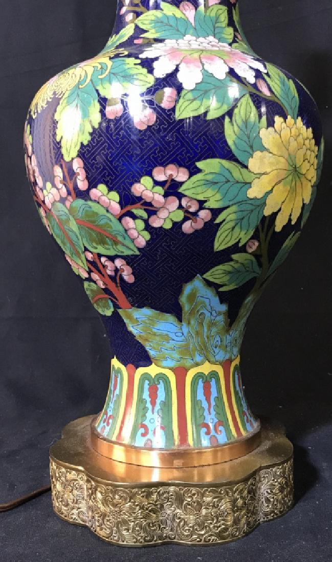 Asian Cloisonné Style Table Lamp: Floral cloisonné style metal lamp body on embossed metal base. Lamp has not been tested. Measures approx 31 inches in height including harp by 7.5 inches in diameter. Missing finial. Cloisonné style