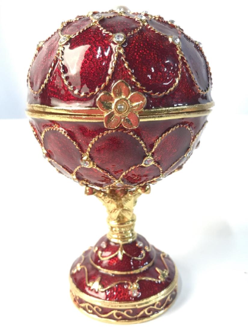 Intricate Faberge Style Music Box: Music box has spherical shape. Contains tones of red, and gold. Piece is Pedestaled. Interior has cream tone. Measures approx 6 inches tall 3.5 inches wide. decorative accessory, luxury home decor, va