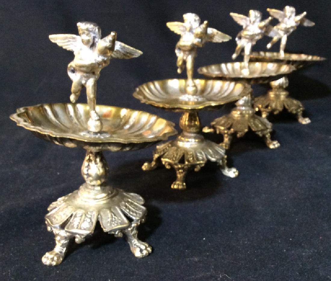 Lot 5 Silver Toned Pedestal Cherub Dishes: Lot includes 4 footed Pedestaled Cherub dishes. Largest pieces measure approx 4.5 inches tall 3 inches wide. Each appear to possibly be silver plated. dishes, tableware, tabletop decor, cupids, puttis