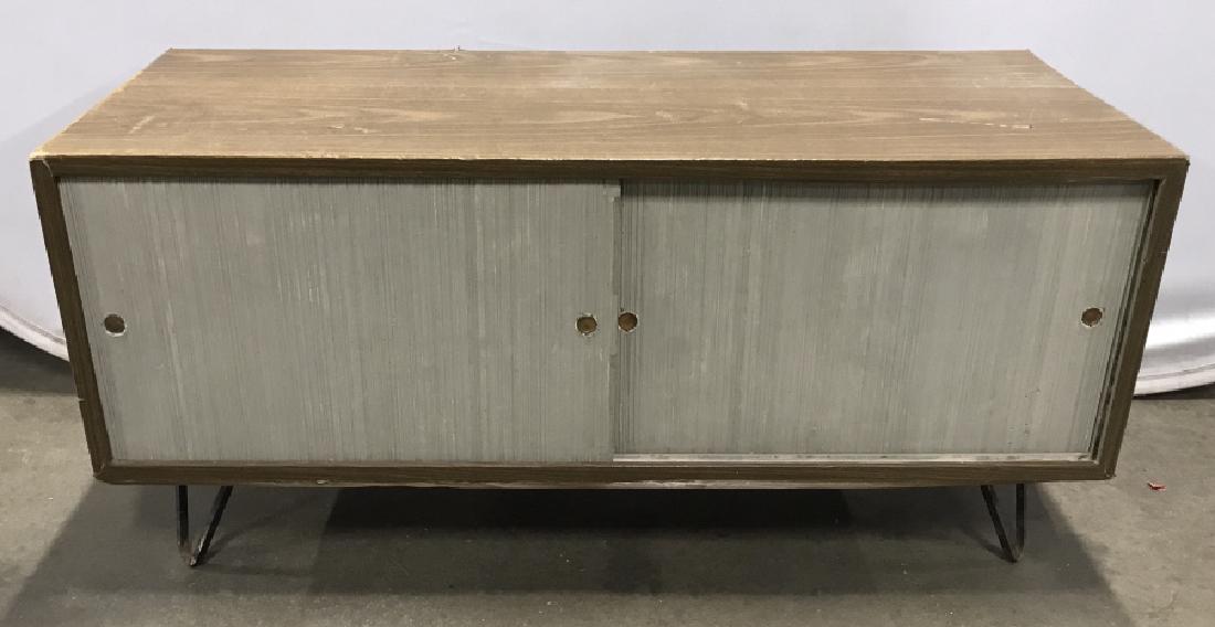 MCM Vintage Wood Toned Cabinet On Metal Legs: MCM Vintage Cabinet On Metal Legs And two sliding door, finish appears to be laminate or Vinyl covering, damage to areas of exterior and surface wear due to age and use, measures approximately 42 inch