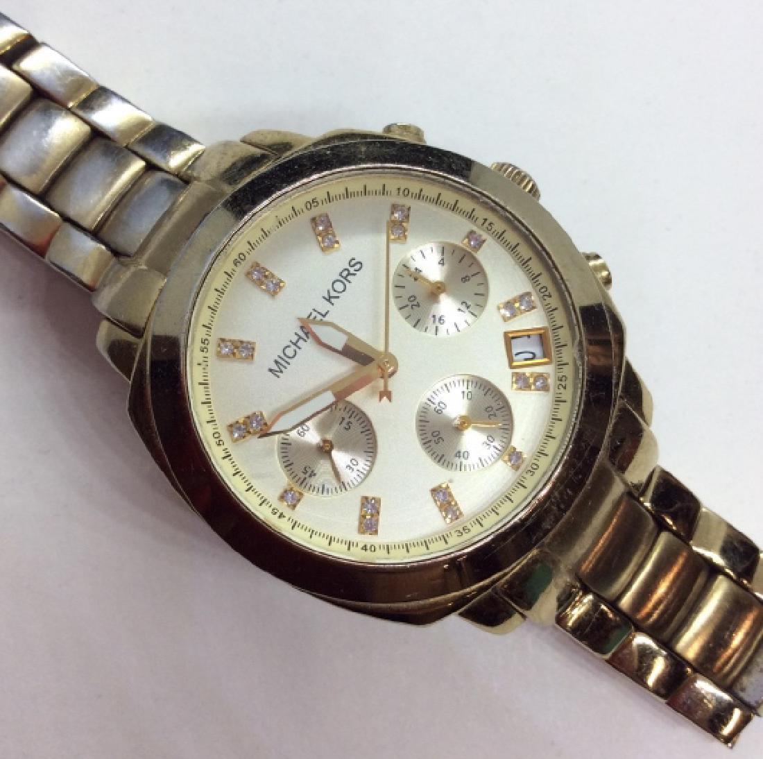 MICHAEL KORS Gold Toned Wristwatch: Gold toned metal Wristwatch. All stainless steel Wristwatch. Not tested, Measures approx 3 in in diameter. Some wear to metal and scratches to watch face. Fashion accessory, wearable, designer fashion