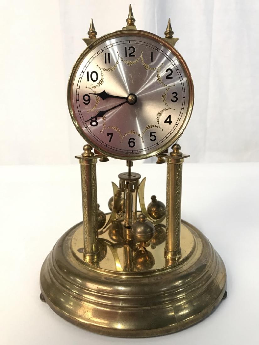 Gold Toned Metal Dome Clock: Clock face Reads MADE IN GERMANY. Piece is gold toned with silver toned clock face. Piece possible has brass elements. Has glass dome. Measures approx 12 inches tall 7.5 inches wide. Rotating spherica
