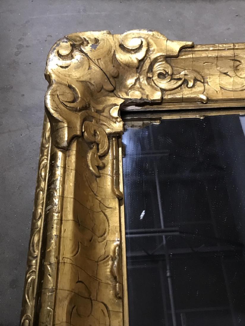 Mantel Mirror in Gold Tone Carved Wood Frame: Frame is gold tone carved gesso over wood frame. Possibly antique. Measures approx 31 inches in height by 35 inches in width. There is superficial cracking in frame, appears stylistic or consistent wi