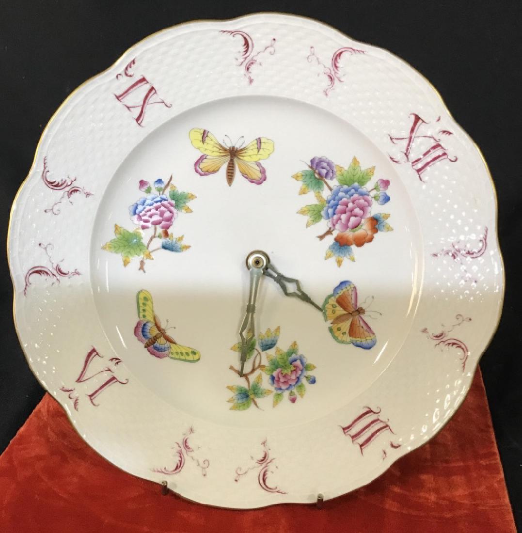 Hand Painted Porcelain Plate Clock, Hungary: HEREND Fine Bone Chine Plate. Stamp Marked. Working Condition. Flower and a Butterfly Motif with Roman Numerals, several faded. gold toned rim, no fading color. Wall Mount. Porcelain Wall Clock, Hunga