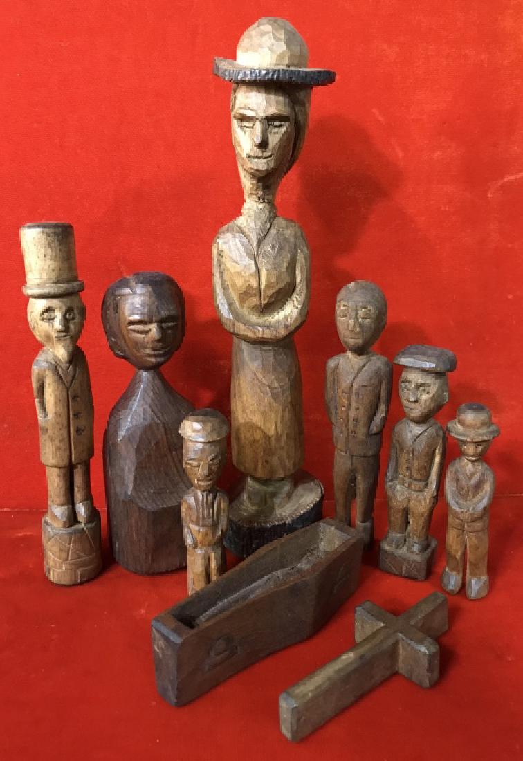 Lot 9 Wood Carved Folk Art Figurines: Lot 9 wood carved folk art figurines, including 7 figures, a coffin with a man inside, and a cross. Largest figure measures approx 7.75 inches in height. Smallest figure measures approx 2.75 inches in