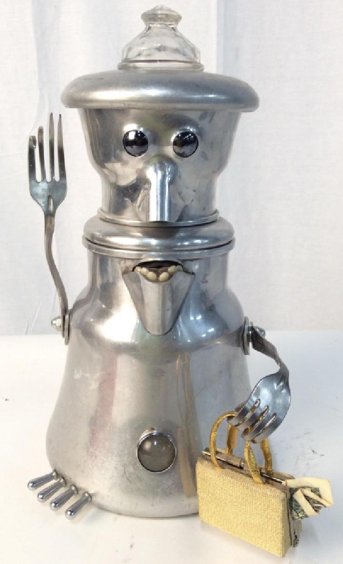 Silver Toned Metal Coffee Pot Sculpture: Piece is silver toned. Sculpture resembles a robot with fork hands, spout mouth and nose, eyes and miniature purse. Created from metal coffee pot, Measures approx 14 inches tall 7 inches wide. Folk ar