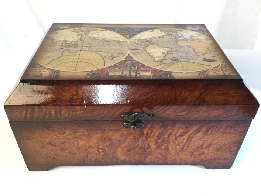 Lidded Wooden Keepsake Box: Keepsake Box is Wooden. Contains images of the globe. Piece is dark wood tone. Contains metal locking mechanism on front of piece. Box has lid. Measures approx 12 inches long 6 inches tall, 8.5 inches