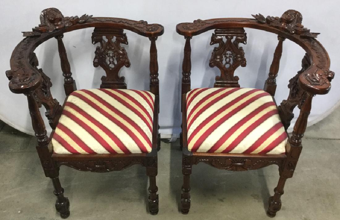 Pair Ornately Carved Mahogany Corner Chairs: Pair of 20th century Vintage Carved Mahogany and Upholstered Corner Chairs. Griffin figures flanked at the back rest and high relief putti/angel figure in center ornate carved patterns on arm rests an