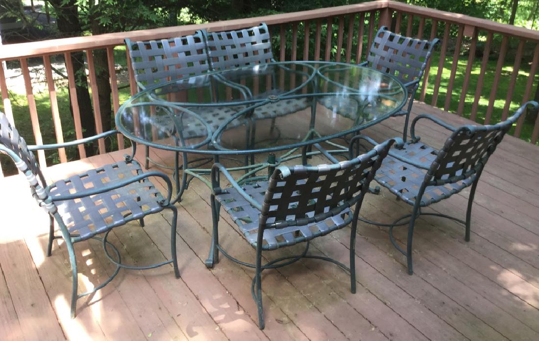 Lot 8 BROWN JORDAN Outdoor Dining Furniture Set: Lot includes 1 glass top dining table, 6 armchairs, 1 chaise lounge chair, and 1 umbrella w/ stand. Furniture has metal framing, deep blue green in tone. Glass top Dining table is oval in shape. Armch