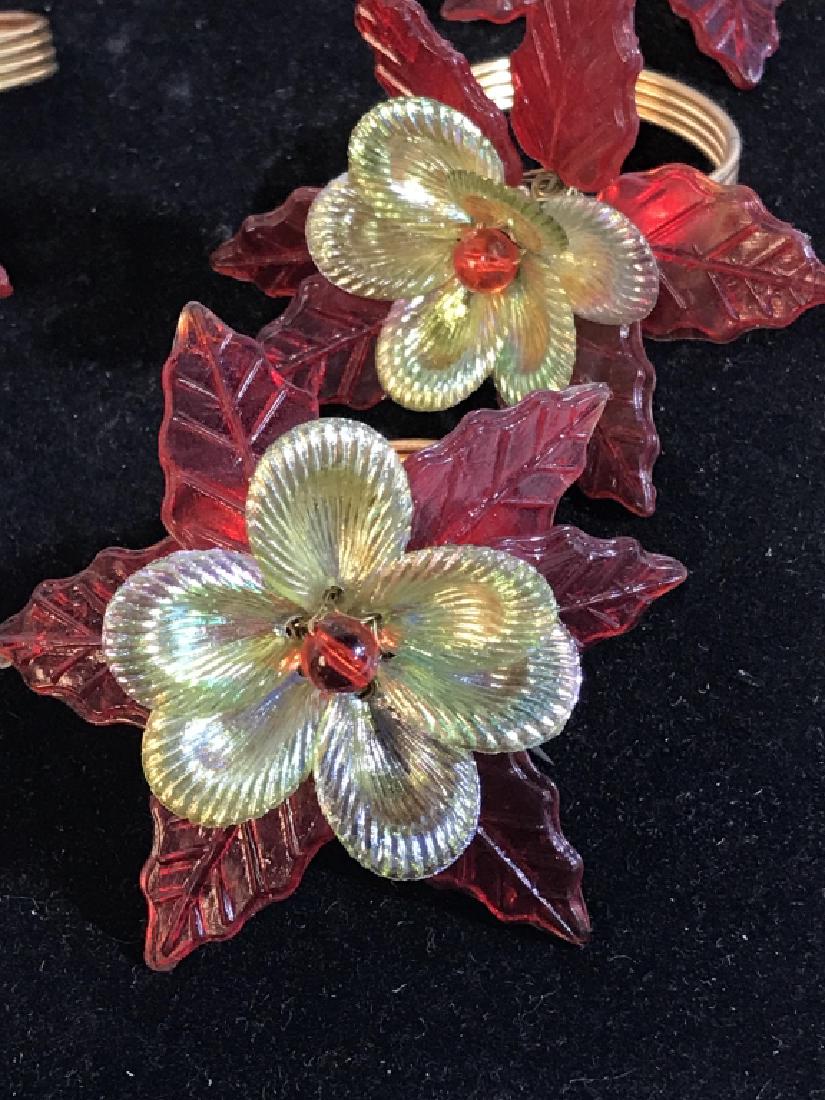 Set 12 Vintage Poinsettia Flower Napkin Rings: Plastic Flower and Gold Tone Metal Napkin Ring. Poinsettia Measures Approx 3 in. point to point. Ring measures approx 1 1/5 in. dia. Did you know the Poinsettia Plant is indigenous to Mexico? They are