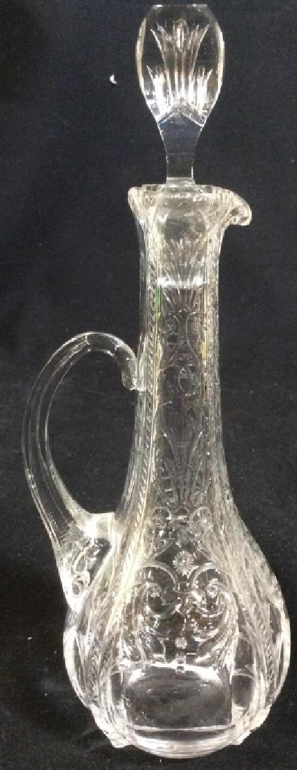 Cut Glass Decanter Pitcher W Stopper: Decanter is Cut Glass. Piece includes stopper. Contains beveled ornate & floral detail. Piece measures approx 10 inches tall 4 inches wide with spout and handle. decanter, pitcher, tableware, tabletop