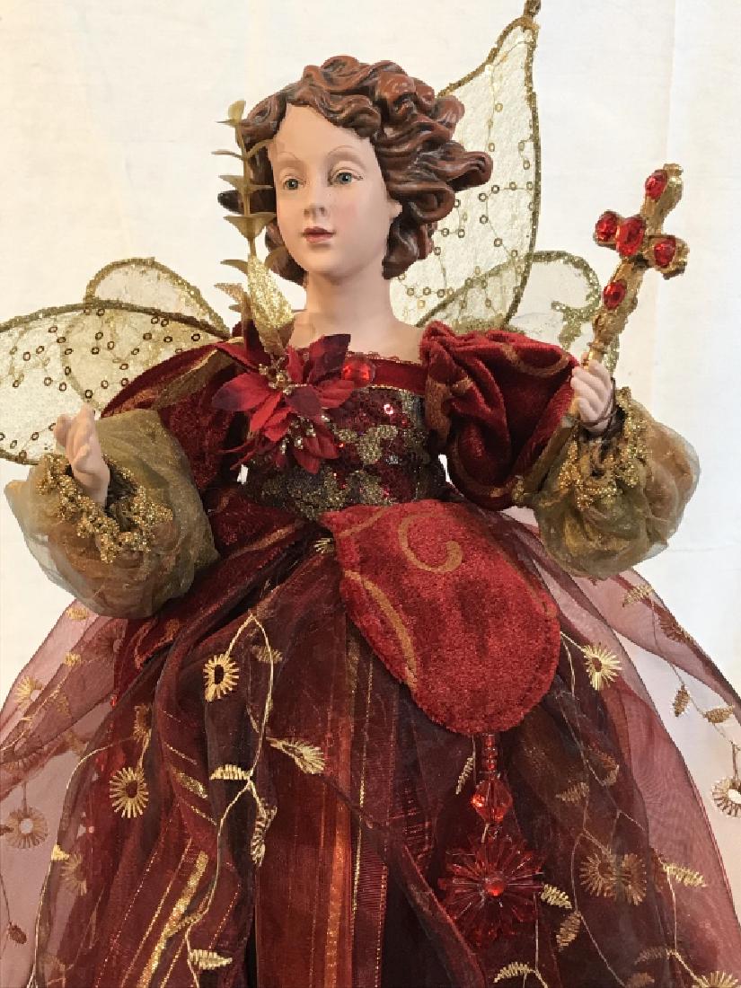 Angle Christmas Tree Topper: Dressed in Dark Red Taffeta, Ribbons and Velour. She is Holding Cross with rhinestone details And Adorned With Golden Angel Wings. Stands Approx 16 in. tall. Sturdy plastic cone cupping underneath to
