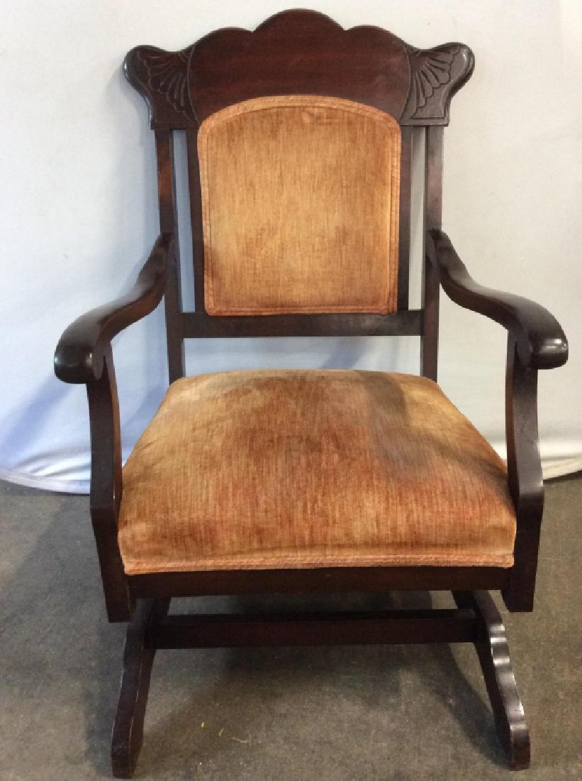 Vintage Carved Wooden Cushioned Rocking Chair: Chair is vintage. Contains carved wooden detail. Piece has dark coral toned upholstery. Measures approx 37 inches tall 30 inches deep 23 inches wide. Arm chair lounge chair, home furnishings