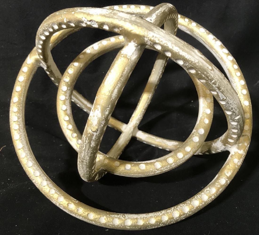 Gold Toned Metal Sculpture: Piece is gold and white toned. Appears to be metal. Measures approx 10.5 inches wide. Has some cracks. Shape resembles gyroscope. decorative accessory, home accent, shelf piece, decorative arts and ac