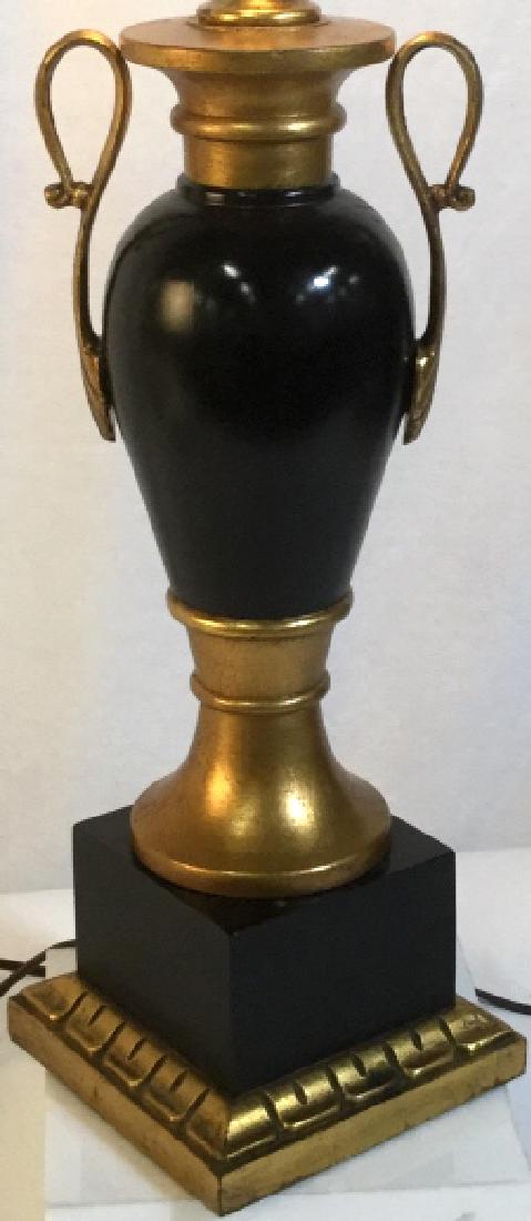 Black and Gold Urn Shaped Table Lamp: Material Possibly Composite or Wood. Working Condition. Square Base with main shape vase/ vessel. Some wear on base. No other surface conditions noted. No harp or shade. Approx 22.5 in H from base to 