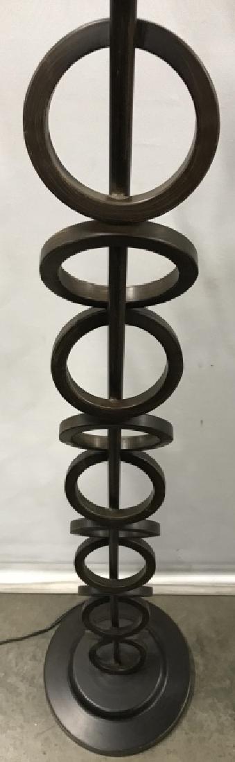 Bronze Toned Metal Lamp W Stacked Ring Detail: Floor lamp is bronze toned. Center of piece Contains slanted ring shaped detail. Base is circular. Piece includes finial. Measures approx 61 inches tall 10.5 inches wide. floor lamp, home lighting, de