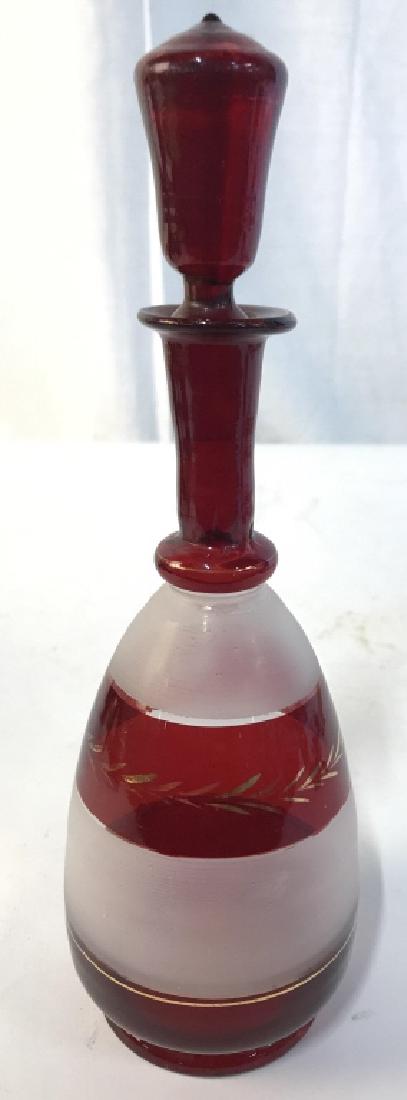 Red Toned Frosted Decanter W Stopper: Cranberry Glass Decanter. Piece is red toned & frosted. Contains gold toned detail. Piece includes stopper. Measures approx 9 inches tall 3 inches wide. Decanter, decorative accessory, tableware, shel