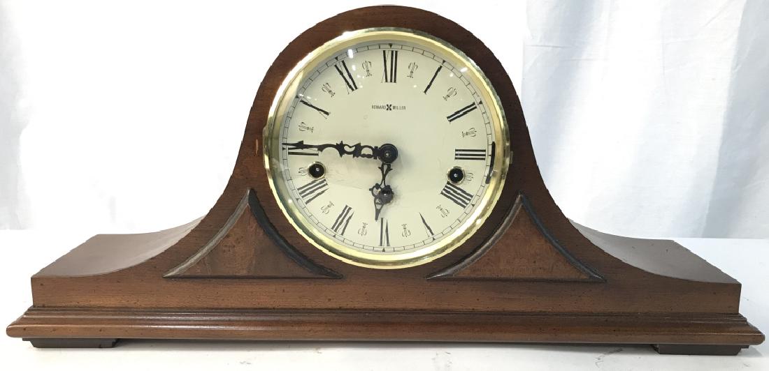 Howard Miller Mantel Clock: Clockface reads HOWARD MILLER. Piece appears to be carved wood. Clock face is cream toned with black toned Roman numerals & Black Toned hands. Clockface window open. Measures approximately 20.5 inches