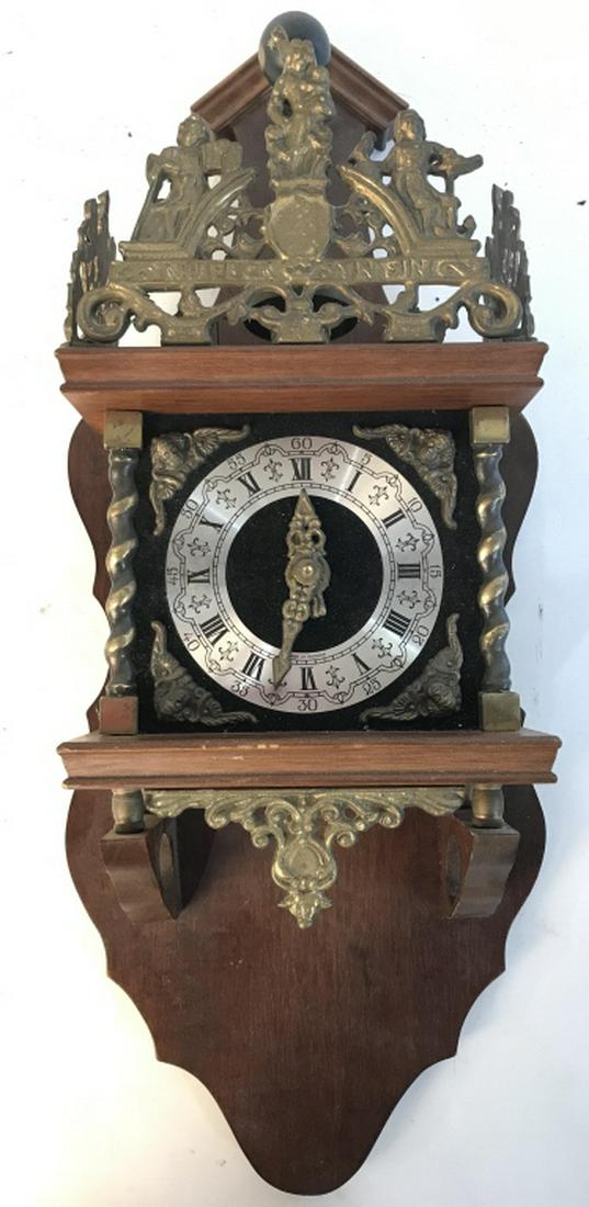 FRANZ HERMLE Wood & Brass Wall Clock: Interior of piece is marked FRANZ HERMLE. piece has carved wooden elements and ornately detailed gold toned brass detail. Clock face is silver toned with black toned Roman numerals. Wall clock, Franz 