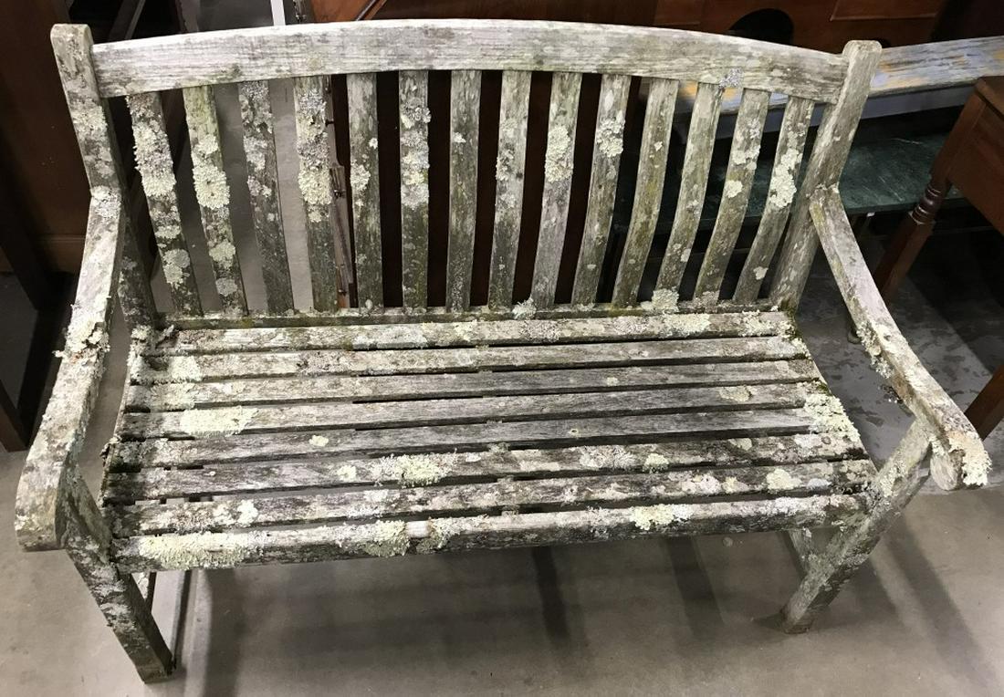 Pair of Outdoor Teak Benches: Pair of outdoor teal benches with backs and arms. Each bench measures approx 34.25 inches in height by 47.6 inches in width by 24 inches in depth. Benches have moss & lichen buildup consistent with ou