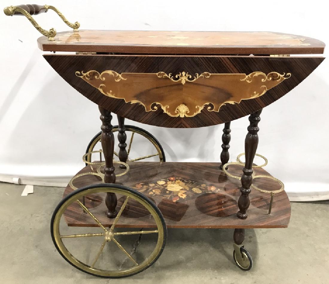 Vintage Intricately Detailed Bar Cart: Bar Cart has intricate floral leaf and vine detail. Piece has 2 large & 2 small wheels. Piece has drop leaf on each side. Lower level contains 6 gold toned metal bottle holders. Handle is wooden with