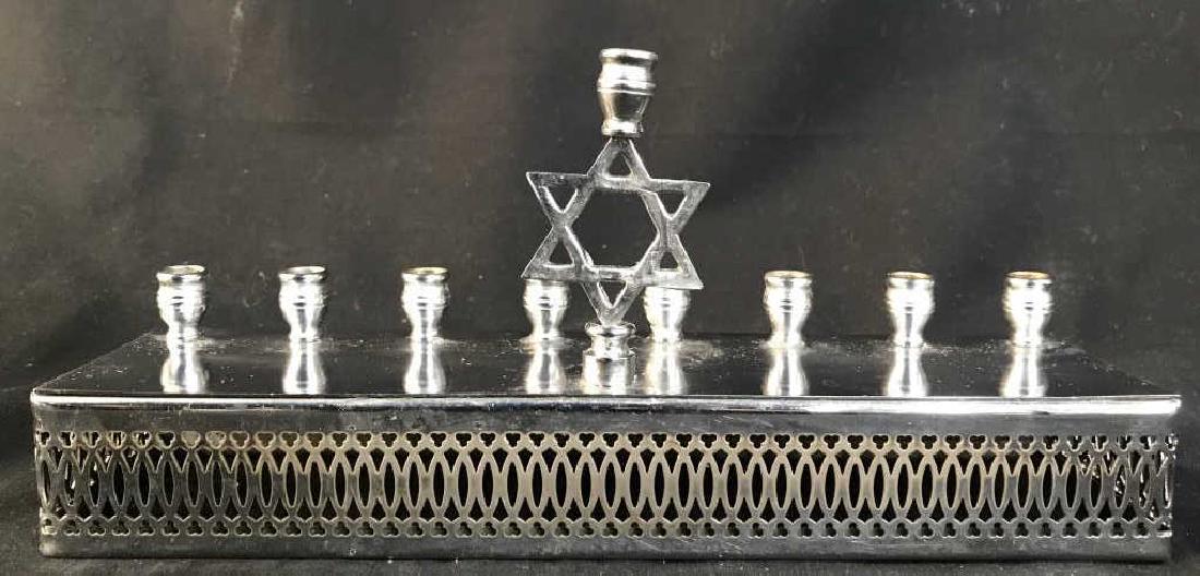 Silver Toned Metal Menorah: Menorah is silver toned & Metal. Possibly silver plated. Contains Star of David in center. Measures approx 10 inches long 4.5 inches tall, 2.5 inches deep. Judaica hebraica, ceremonial accessory, tabl