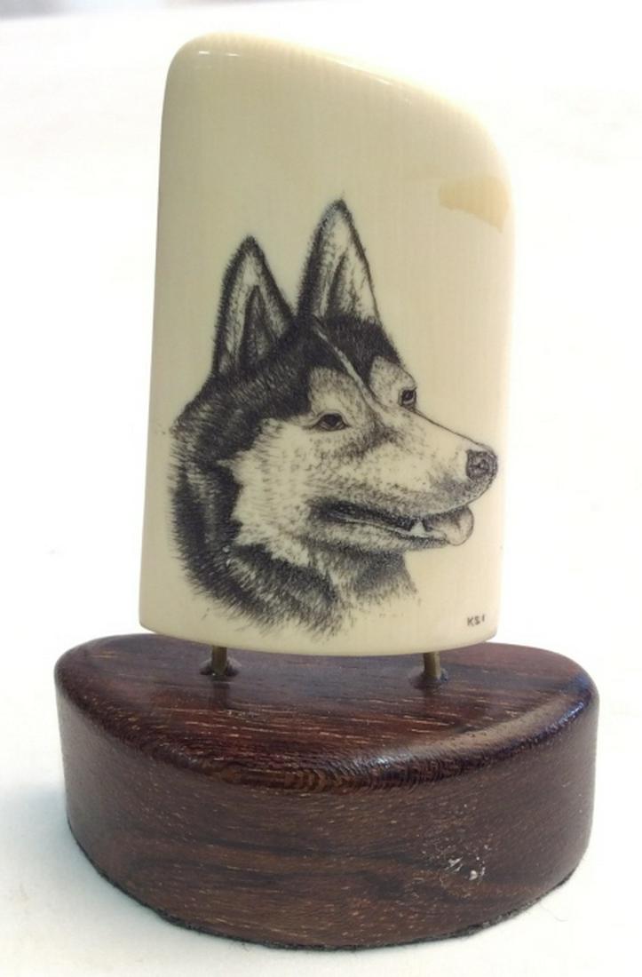 Scrimshaw Wolf Drawing on Whale Bone: Signed scrimshaw wolf drawing on whale bone, held up on a wooden platform. Measures at approximately 3.3 inches tall and 2.2 inches wide. Scrimshaw, scrimshaw Wolf, whale bone art, whale bone scrimsha