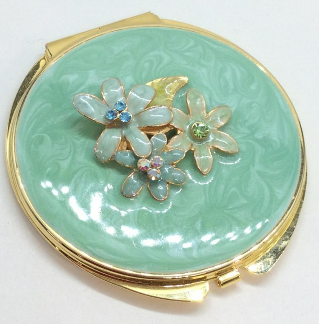 Gold Toned Metal W Enamel Compact Mirror: Compact mirror, gold toned metal, green toned enamel design, Sculptural floral additions to lids swirl enamel and rhinestone details, Measures approx 3 in in diameter women’s accessory, vanity acces