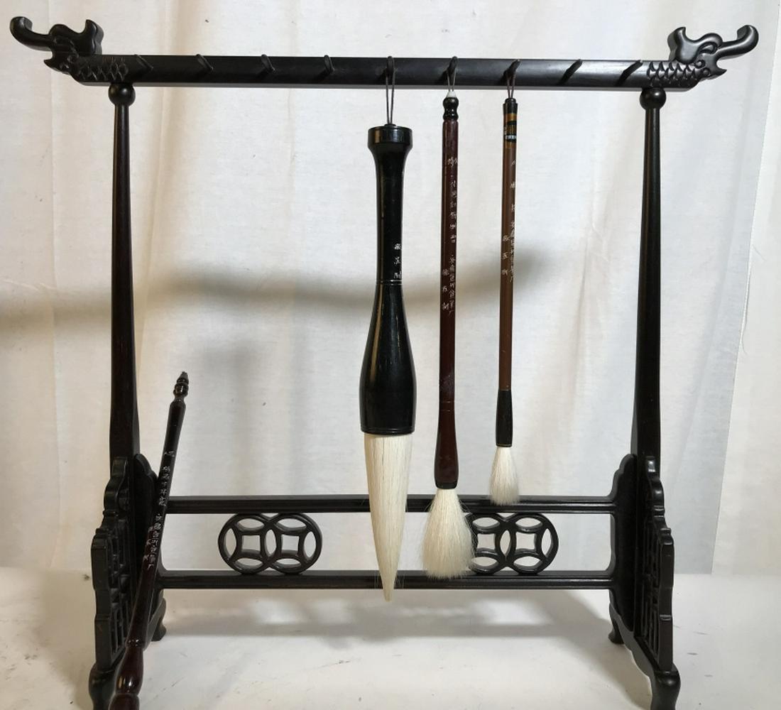 Chinese Wooden Hanging Paint Brush Calligraphy Set: Chinese Dragons adorn the hanging temple structure. 4 different brushes. One unable to place on hook due to damaged strap. Hanging structure measures 15.5 in. H, 18 in. L, 5 in. W. Can disassemble. Po
