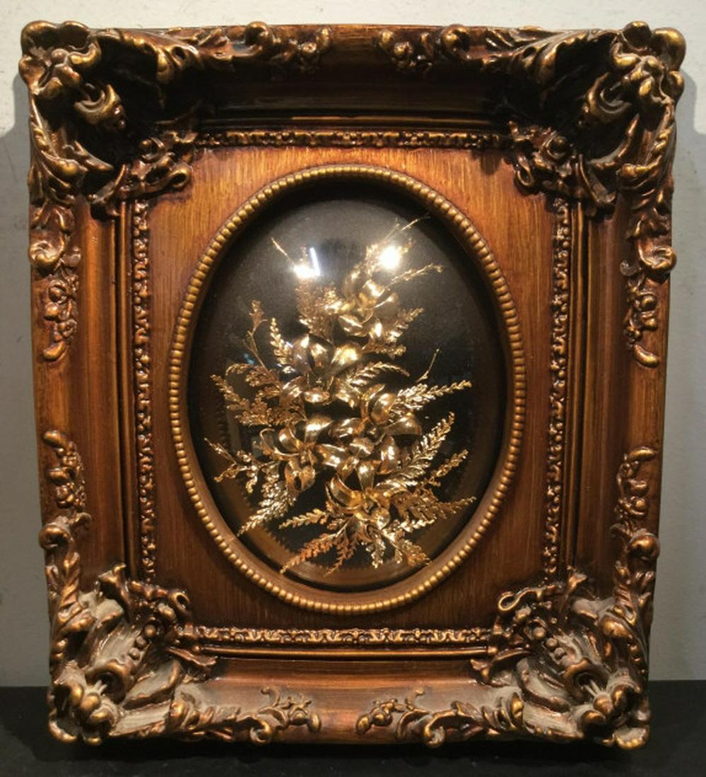 24K Coated Flowers Set in Relief in Frame: Organic flowers coated with 24K gold and set in Relief under convex glass in material composite frame made to appear as wood. Measures approx 14.5 inches in height by 12.75 inches in width by 2.5 inch