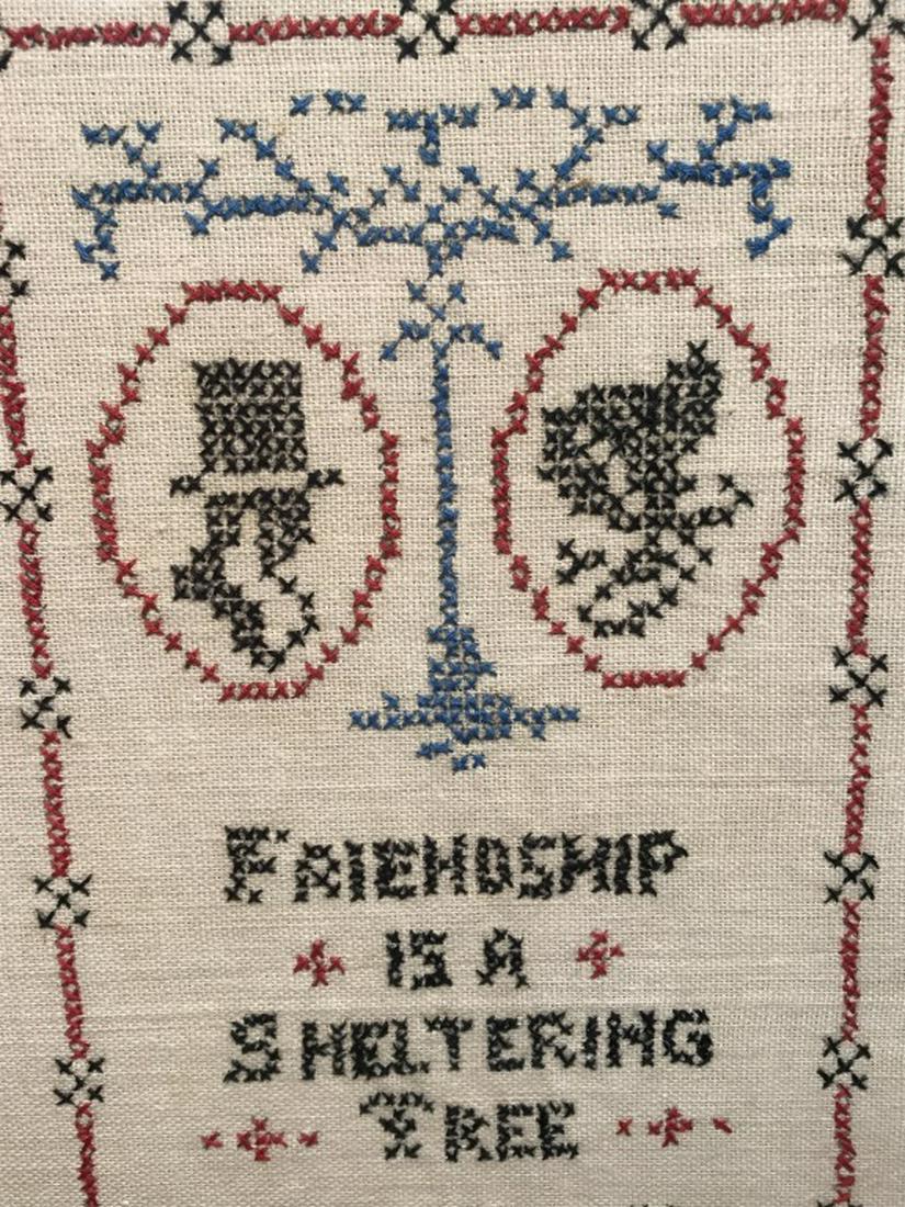 Vintage Motto Sampler, Sheltering Tree: Sampler features the saying ‘friendship is a sheltering tree.’ Embroidered silhouette portraits under tree motif, along with patterned border. Sampler is set behind glass in wood frame. Frame meas