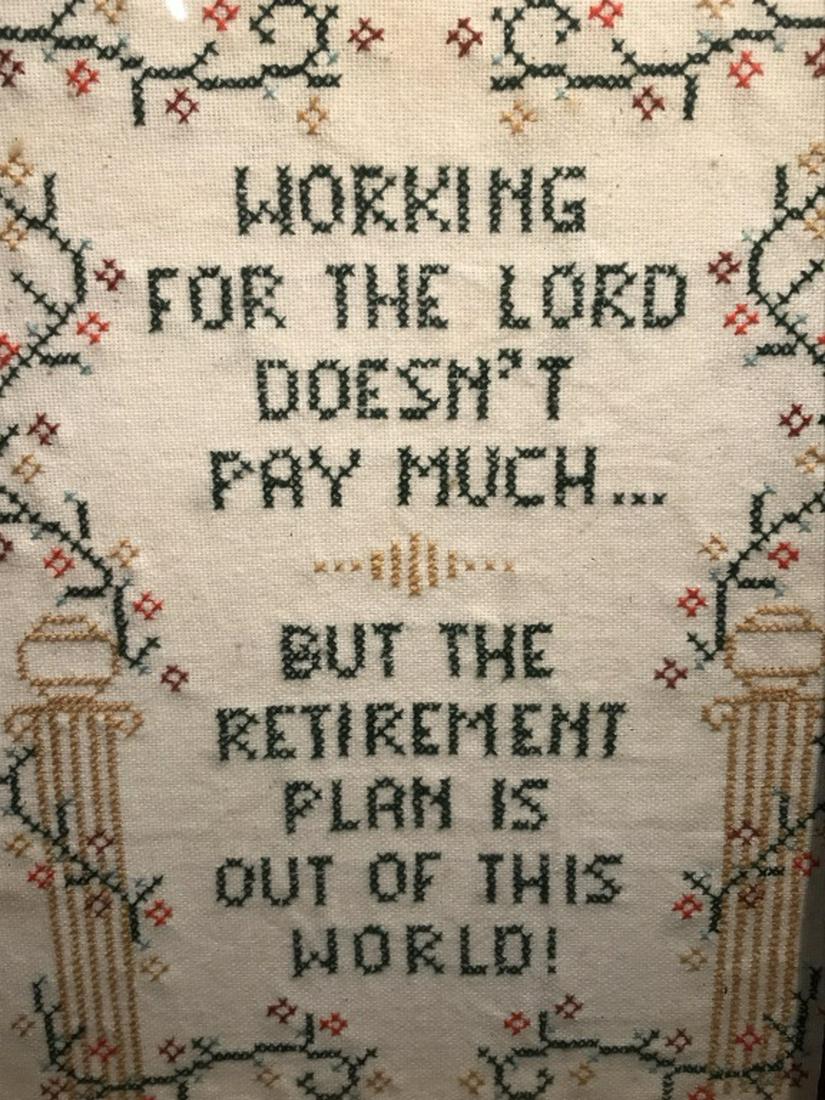 Vintage Humor Motto Sampler: Sampler features the saying ‘Working for the Lord doesn’t pay much/but the retirement plan is out of this world!’ Embroidered pedestal motifs with floral pattern border. Sampler is set behind gl