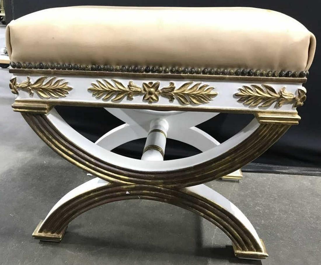 Regency Style Leather Top Wooden Bench: Bench has regency style. Bench is wooden with ornately carved wooden detail. Piece is whir and gold toned with tan toned leather cushion. Measures approx 19 inches tall & long, 14 inches deep. X bench