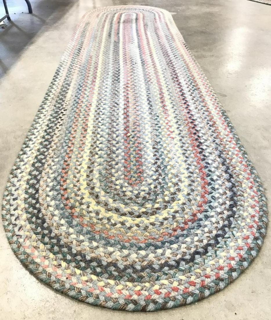 Multi Toned Braided Wool Runner: Runner is multi toned including tones of blue, teal, aqua, pink, slate, cream, and red. Piece has stretched oval shape. Measures approx 108 inches long 27 inches wide. Rug has stain. rug, carpet, home