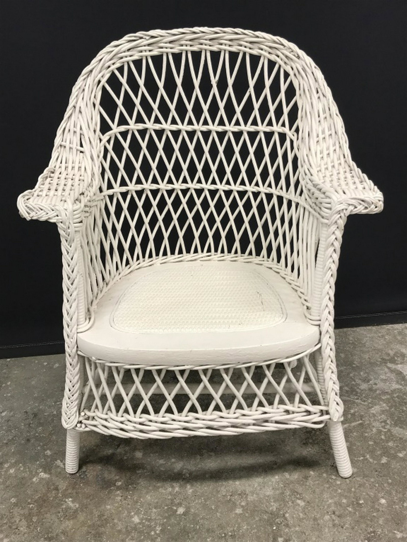 Children’s Painted Wicker Armchair: Armchair is painted white in tone. Measures approx 25 inches in height by 19 inches in width by 12 inches in depth. Some minor surface wear like discoloration in paint. Children’s furniture, armchai