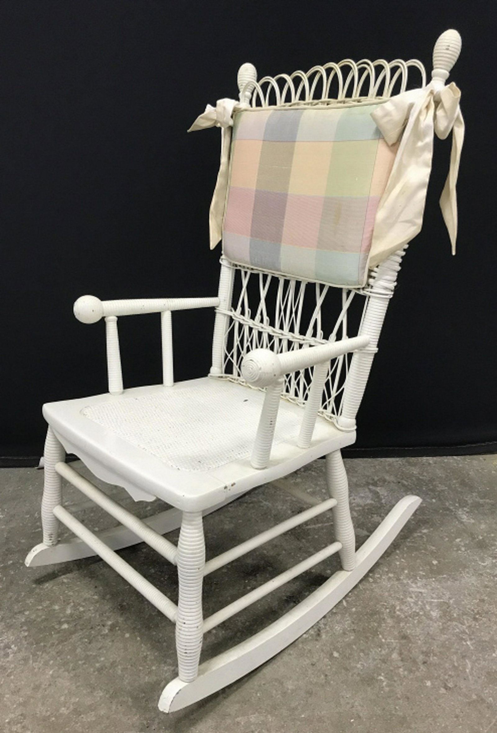 Vintage Petite Painted Wicker Rocking Chair: Rocking chair is painted white in tone. Some surface wear like discoloration and chipping of paint. Measures approx 38.5 inches in height by 22 inches in width by 28.5 inches in depth. petite rocking 