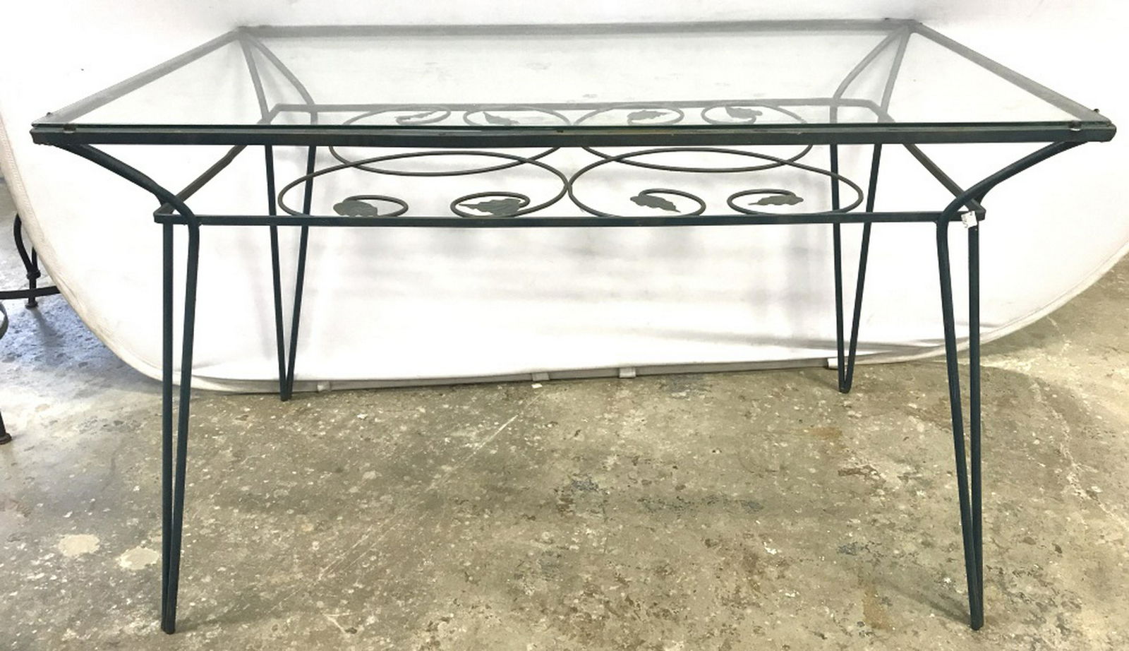 Vintage Outdoor Glass Top Metal Dining Table: Dining table has glass top with vine & leaf detailed decorative tier below it. Possibly iron metal, deep sea green in tone. Measures approx 29.75 inches in height by 48.25 inches in width by 28.25 inc