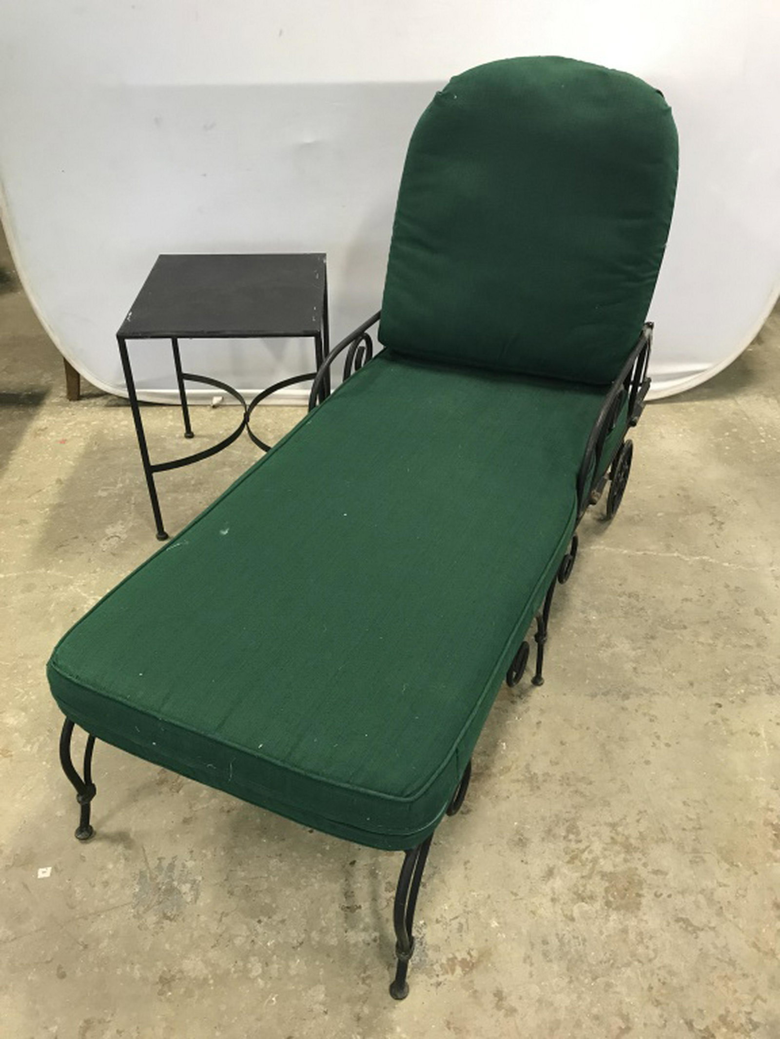 Pair Outdoor Metal Patio Chaise Lounges W Table: Lot includes 2 Adjustable chaise lounges w removable seat cushions and 1 side table. Matches LOTS 563 & 571. Furniture is black in tone, possibly iron metal. Lattice style detailing. Forest green tone