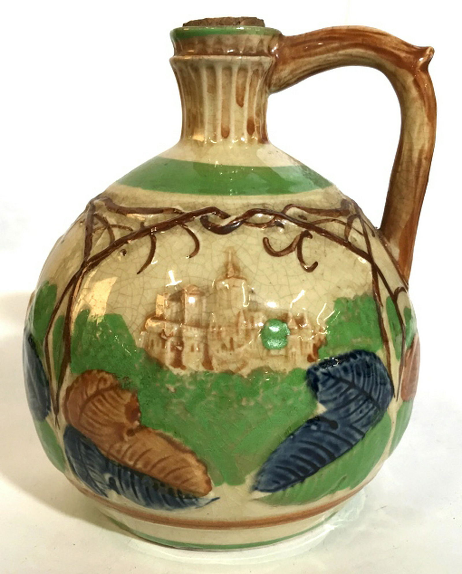 Painted Ceramic Relief Wine Jug Scenes of vines and: Scenes of vines and grapes leaves with ancient hill cities in the background. Includes cork which has writing on it, illegible. Underside written Made in Japan. Height 7.5 in. Circumference 18.5 in. G