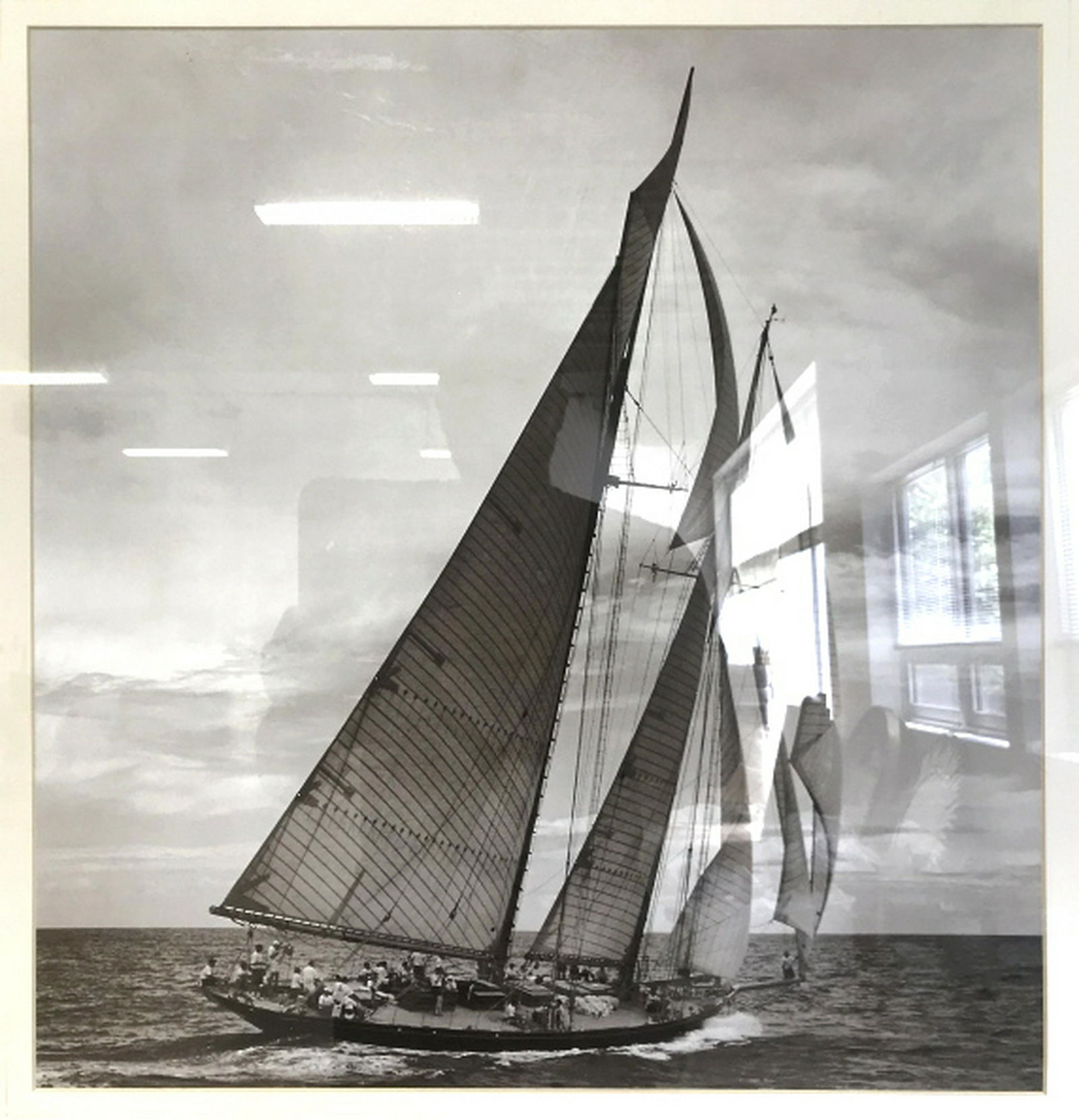 Framed B&W Print of a Sailboat Black and white print of: Black and white print of a sailboat on the water. Print is matted and set behind plexiglass in wood style frame. Measures approx 34.4 inches in height by 32.4 inches in width with frame. Some minor sc