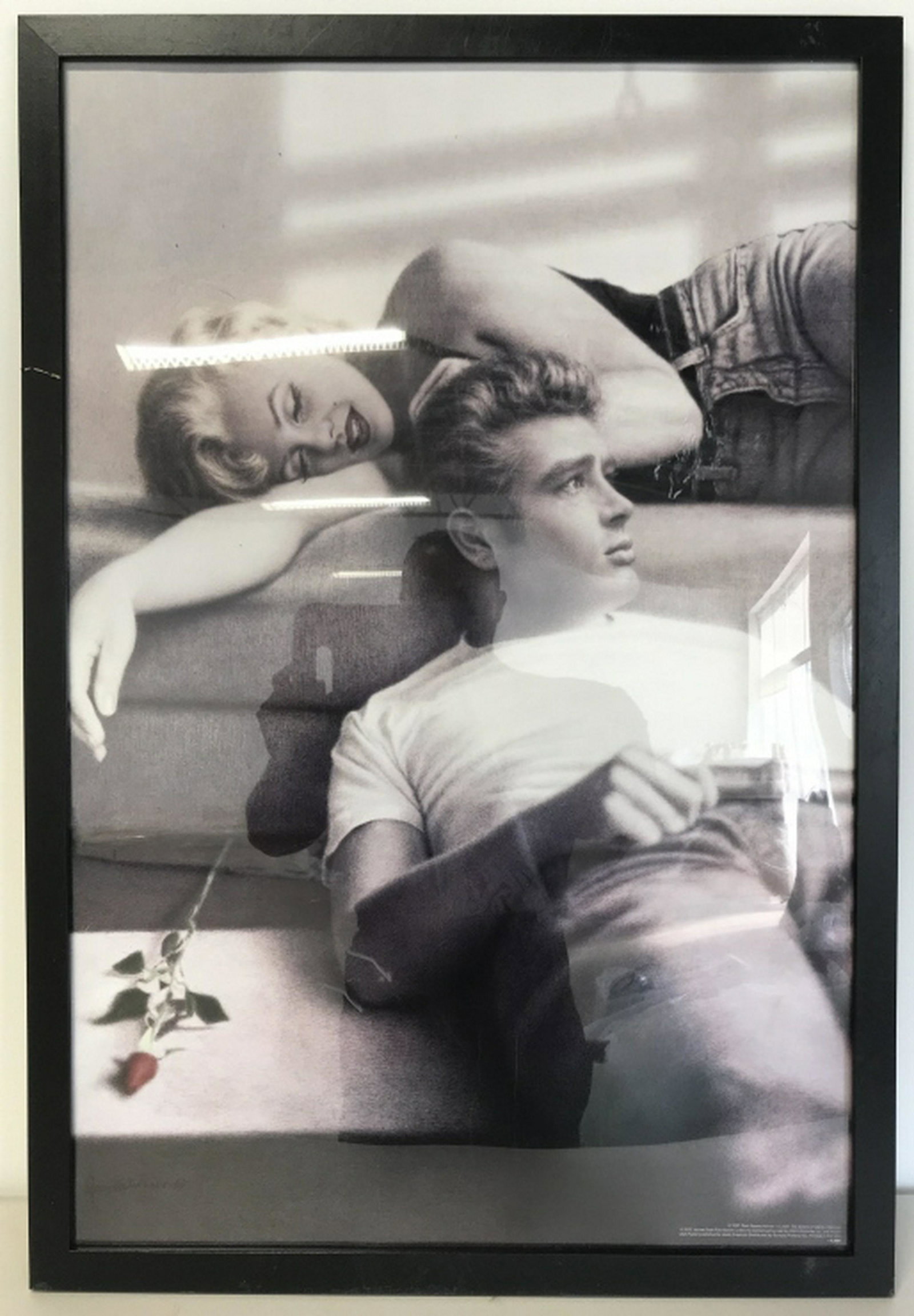 Framed Poster Print, Marilyn Monroe & James Dean Poster: Poster is set behind plexiglass in black tone wood style frame. Some minor surface wear of frame and plexiglass like scratches. Measures approx 38 inches in height by 26 inches in width with frame. Ho
