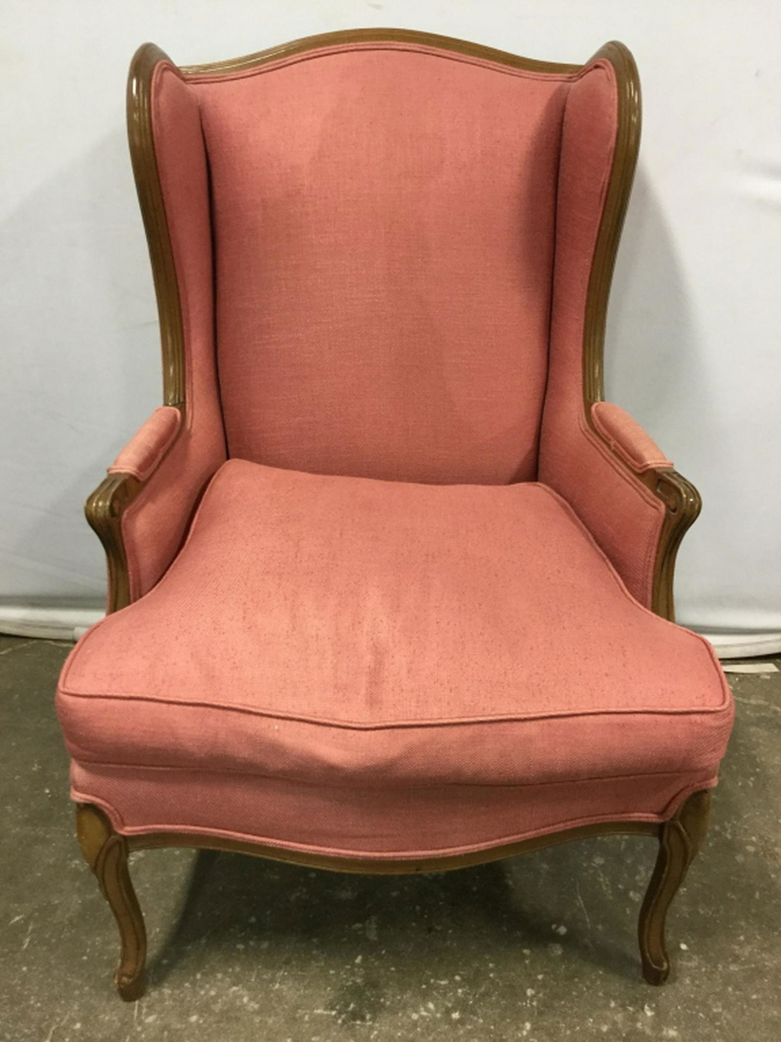 Vintage Upholstered Wingback Chair Chair has carved: Chair has carved wooden detail. Contains coral toned upholstery. Piece has loose seat cushion. Wingback Chair, armchair, Upholstered Chair, Vintage Chair. Measures approx 48 inches tall 30 inches deep
