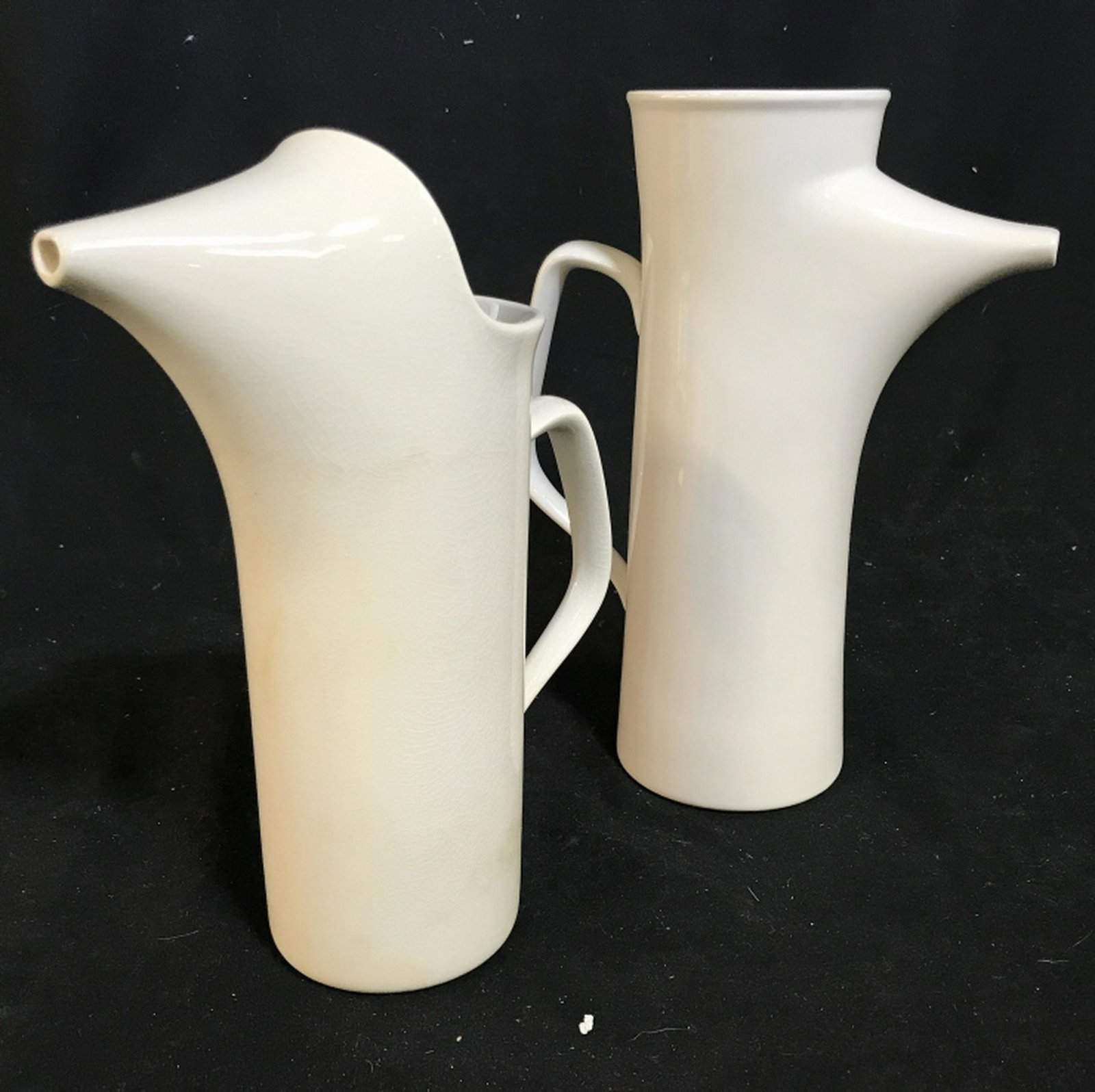 Pair Signed Ironstone White Porcelain pitchers 2 white: 2 white porcelain pitchers. Smaller pitcher stands at approximately 9 inches tall. Larger pitcher measures at approximately 10 inches tall. Simple design. Marked ironstone on the bottom of both pitche