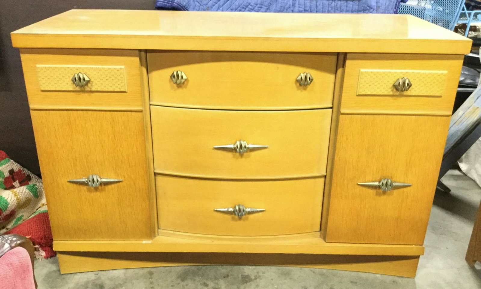 Vintage Wooden Sideboard Sideboard is vintage. Contains: Sideboard is vintage. Contains 3 drawers in center and 2 cabinet doors. One on each side. Piece also has good toned metal handles. Piece measures approx 48 inches long, 32 inches tall 19 inches deep. 