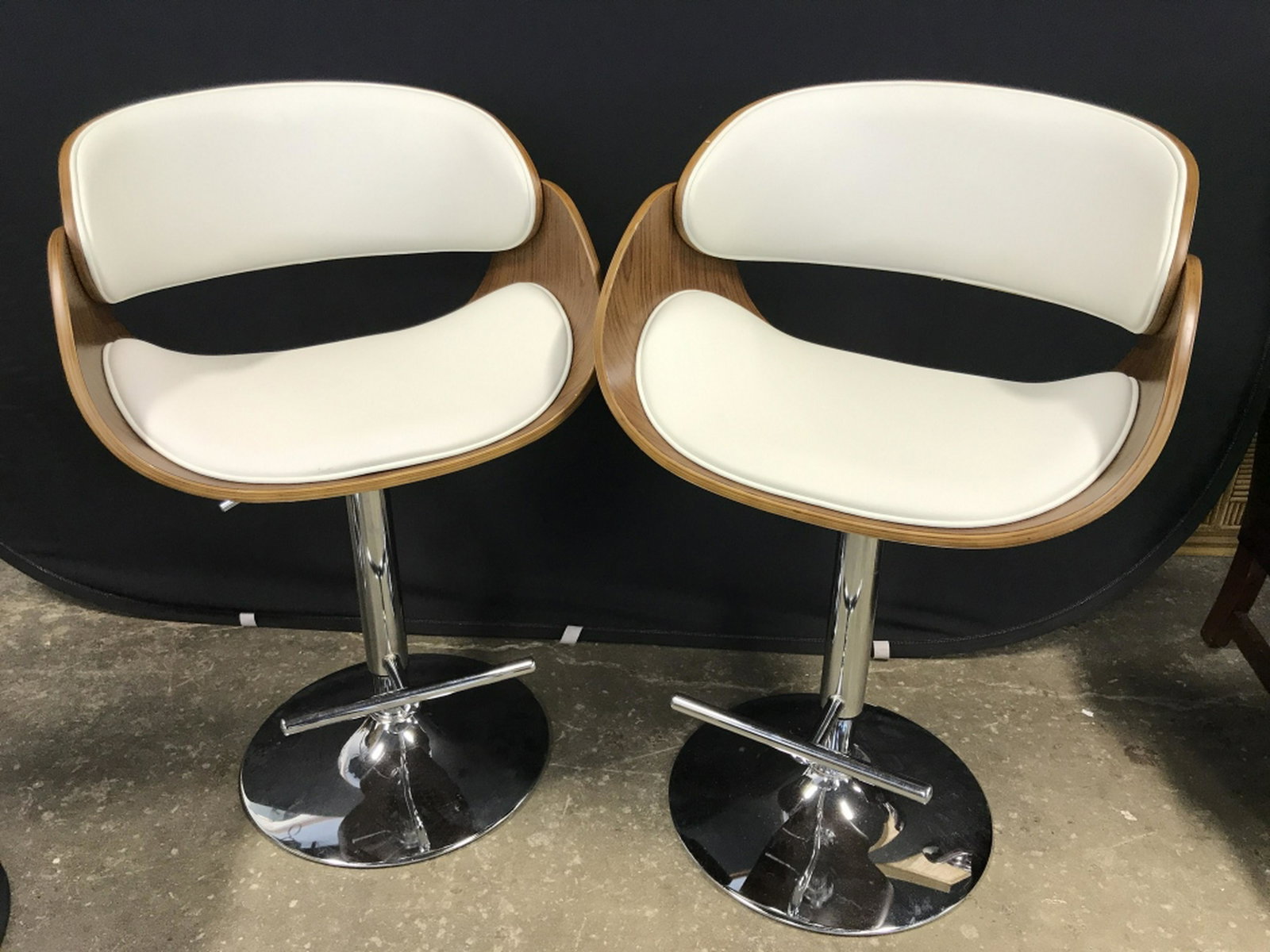 Lot 3 MCM Style Adjustable Bar Stools Lot 3 MCM style: Lot 3 MCM style adjustable bar stools with white tone leather-style upholstery and curved wood-style frame. Seats sit atop chrome base. Lever for adjusting and foot rests. Each measures approx 36.5 in