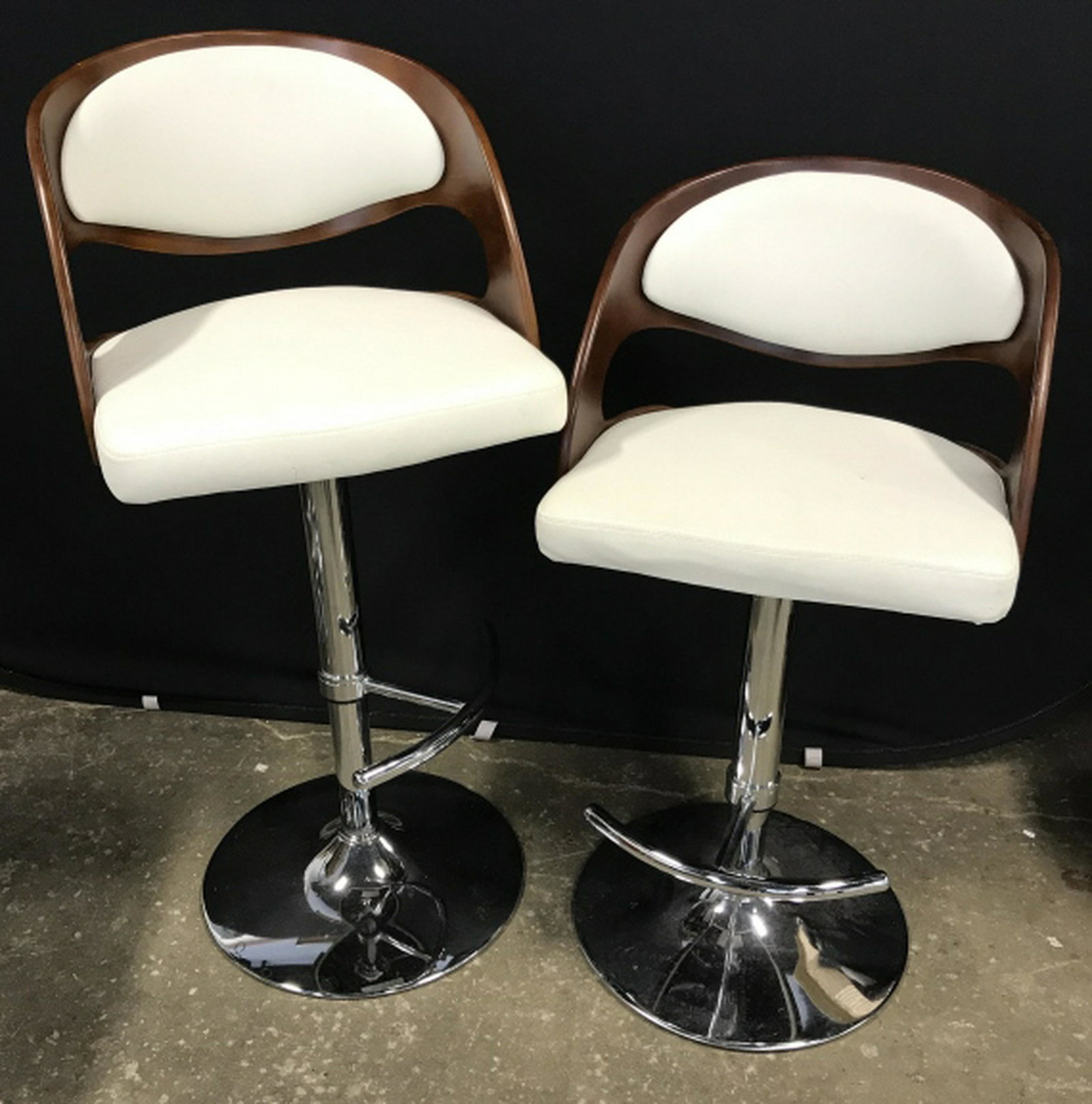 Pair of MCM Style Adjustable Bar Stools Pair of MCM: Pair of MCM style adjustable bar stools with white tone leather-style upholstery and curved wood-style frame. Seats sit atop chrome base. Lever for adjusting and foot rests. Each measures approx 41 in