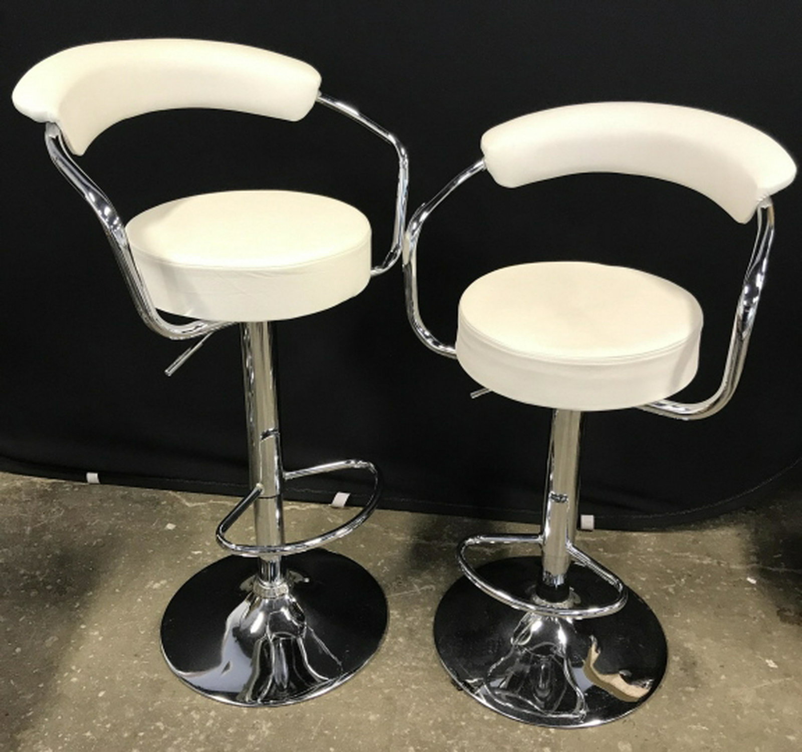 Pair Modern Chrome Frame Adjustable Bar Stools Pair of: Pair of modern style adjustable bar stools with off-white tone leather-style upholstery. Seats have chrome frame. Lever for adjusting with foot rests. Each measures approx 34.5 inches in height by 20.