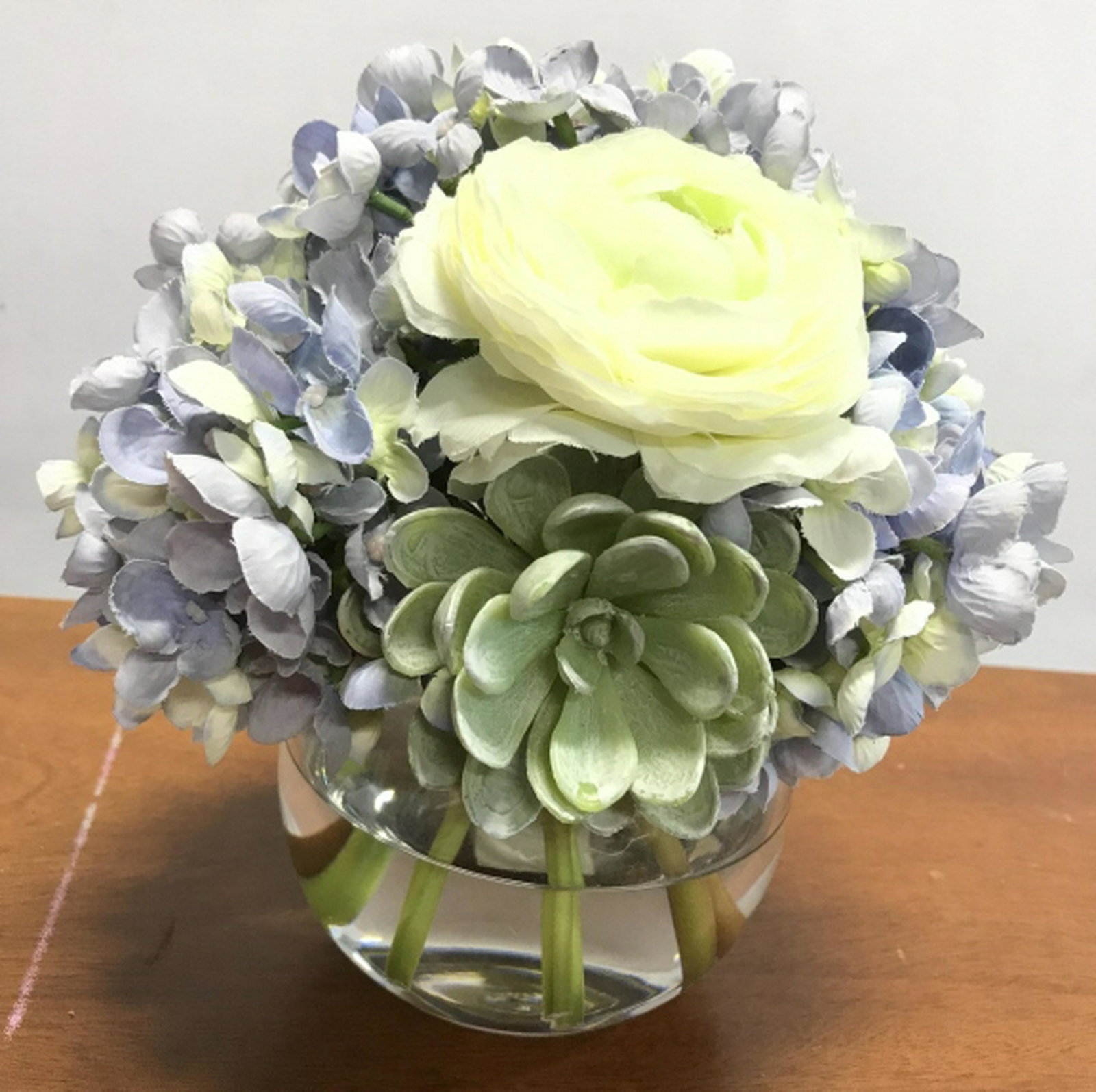 Lavender Toned Artificial Flowers In Glass Vase Piece: Piece has lavender and white toned artificial flowers. Piece measures approx 8 inches tall 5.5 inches wide. Artificial plant, topiary, decorative entryway accessory, interior home decor accessory, out