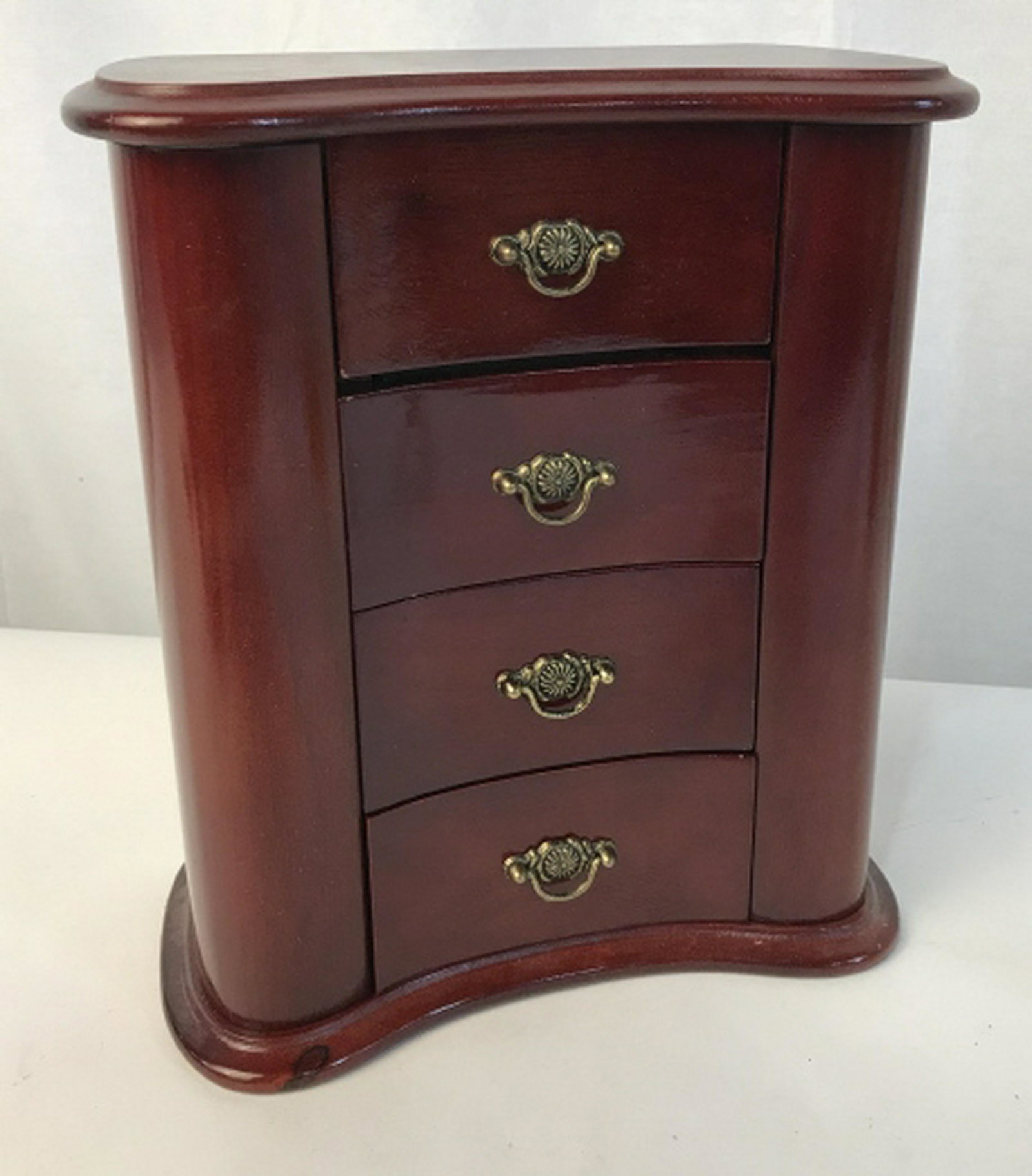 Vintage multi functional musical Jewelry box Color is a: Color is a red wood. Features 3 drawers, a door on each side for necklaces/bracelets and an flip up top with mirror for small accessories. In the back there is knob for a music box. Music box is funct