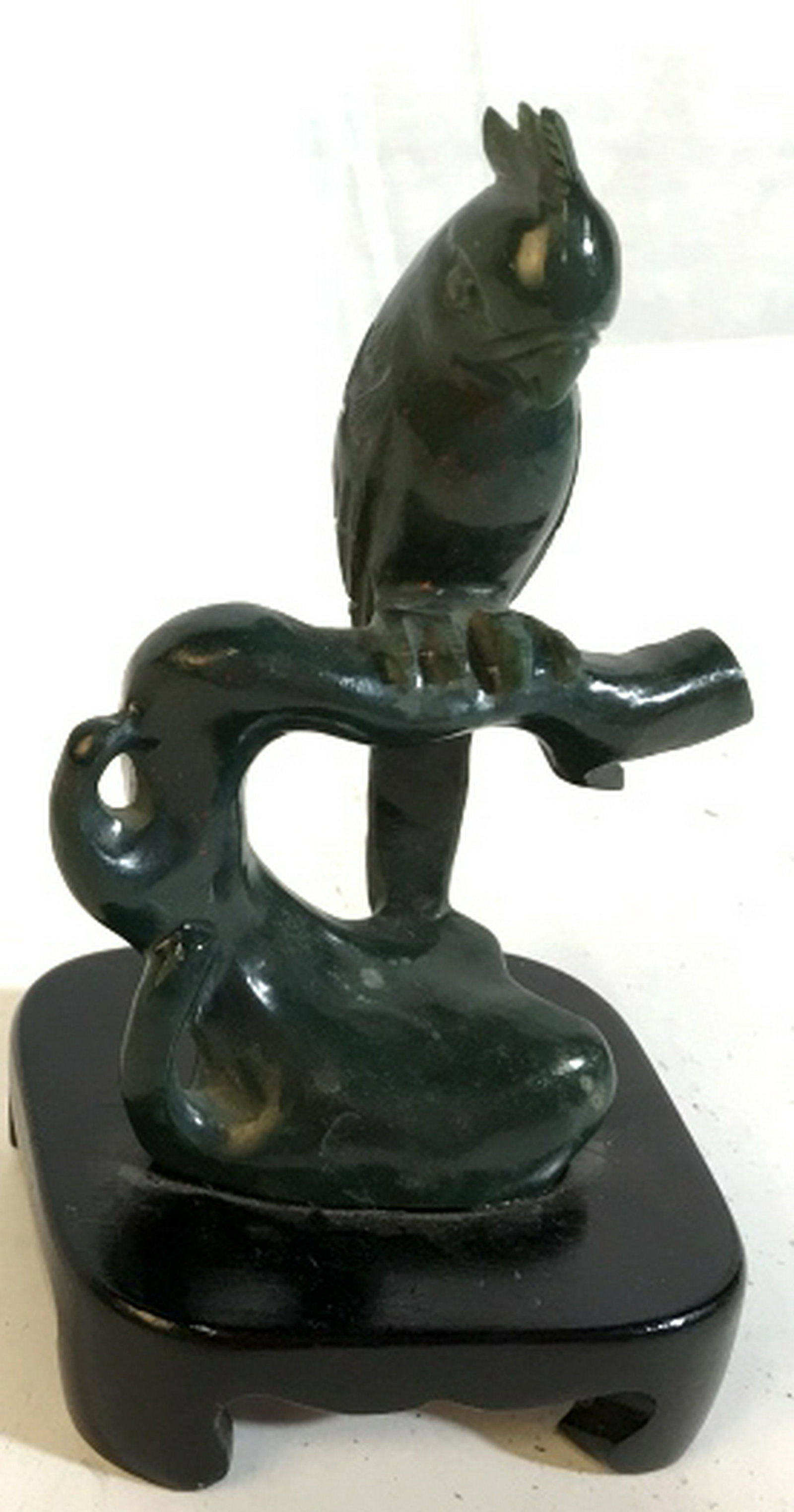 Green Natural Stone parrot sculpture on perch Green: Green parrot on perch. Secured to black wooden base. Sculpture measures approximately 6 inches in height. Parrot and perch has some red speckling on it. Parrot sculpture, bird sculpture, small decorat